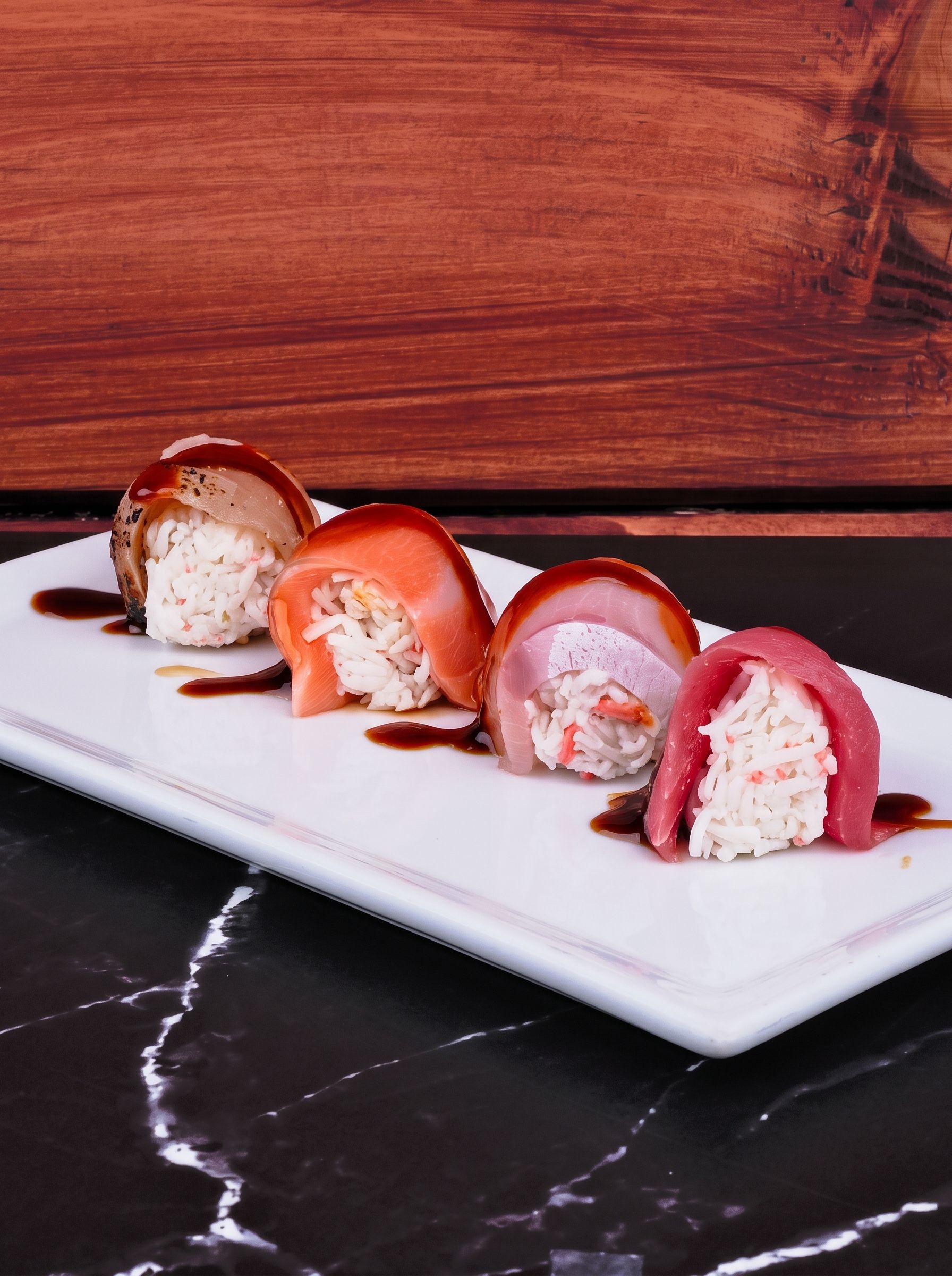 Assorted strawberry and cream dessert rolls on a white platter against a wooden backdrop