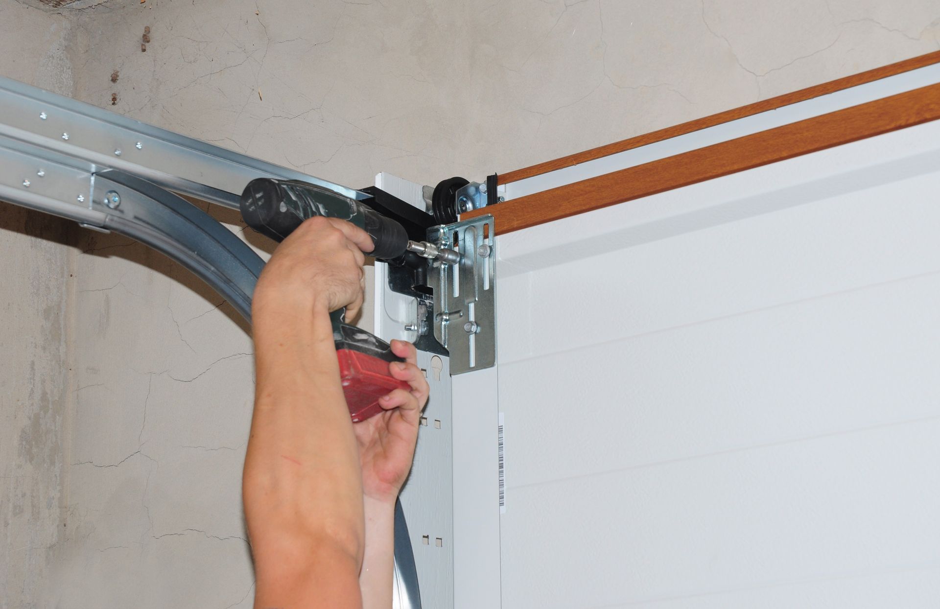 Repairman working on a garage door opener, conducting garage door replacement and repair.