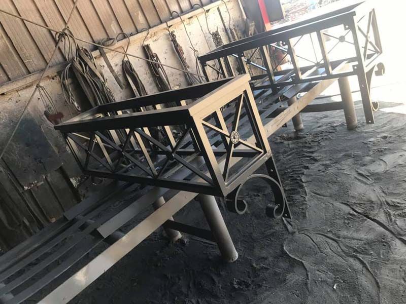 Workshop with metal frames and benches on a dusty concrete floor under a corrugated roof