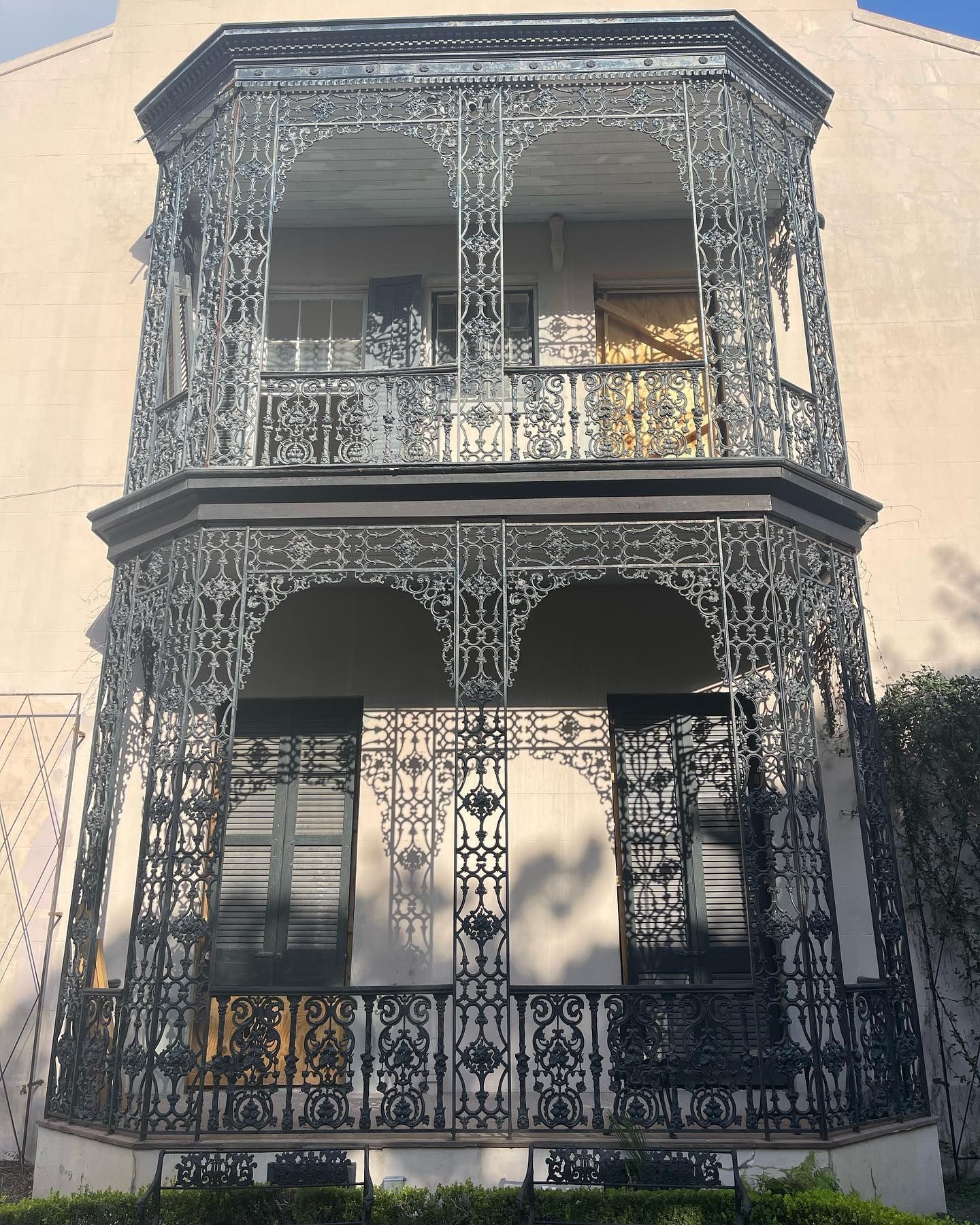 Ornate black wrought-iron balcony facade on a beige townhouse exterior