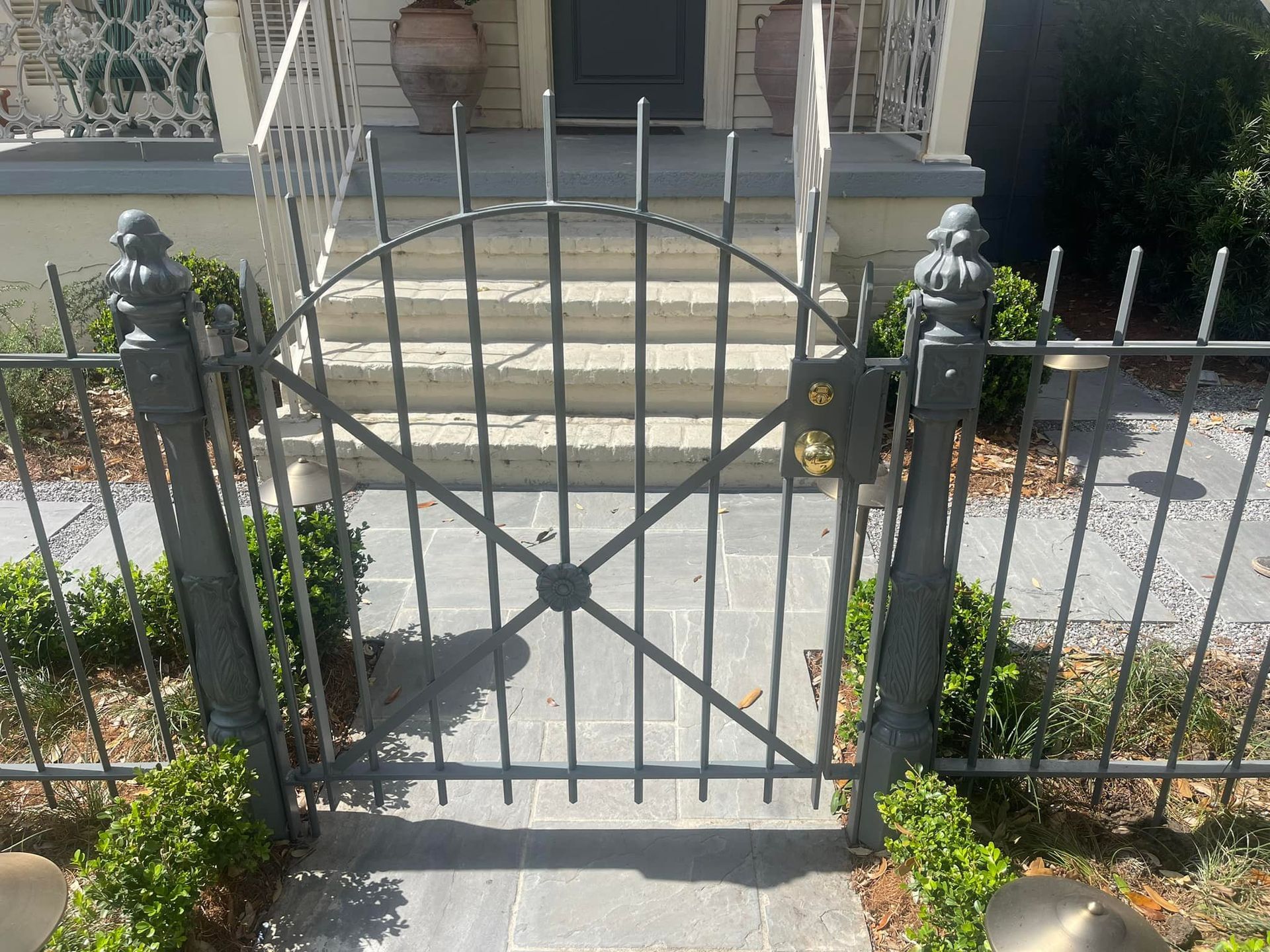 Black metal gate in front of stone steps leading to a house entrance.