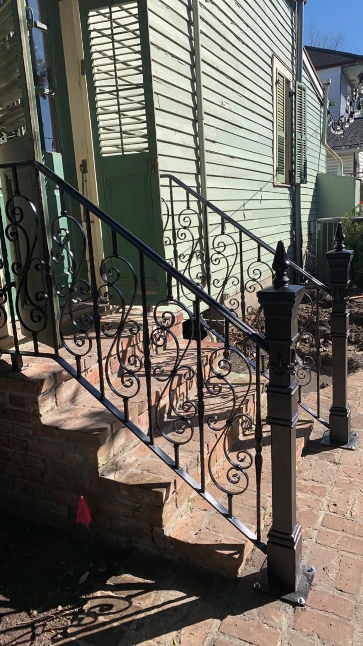 Black wrought-iron stair railing beside a pale green house exterior and front steps.