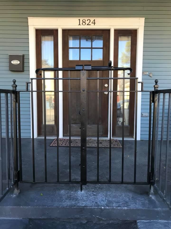 Black metal gate in front of a house entry with the number 1824 above the door.