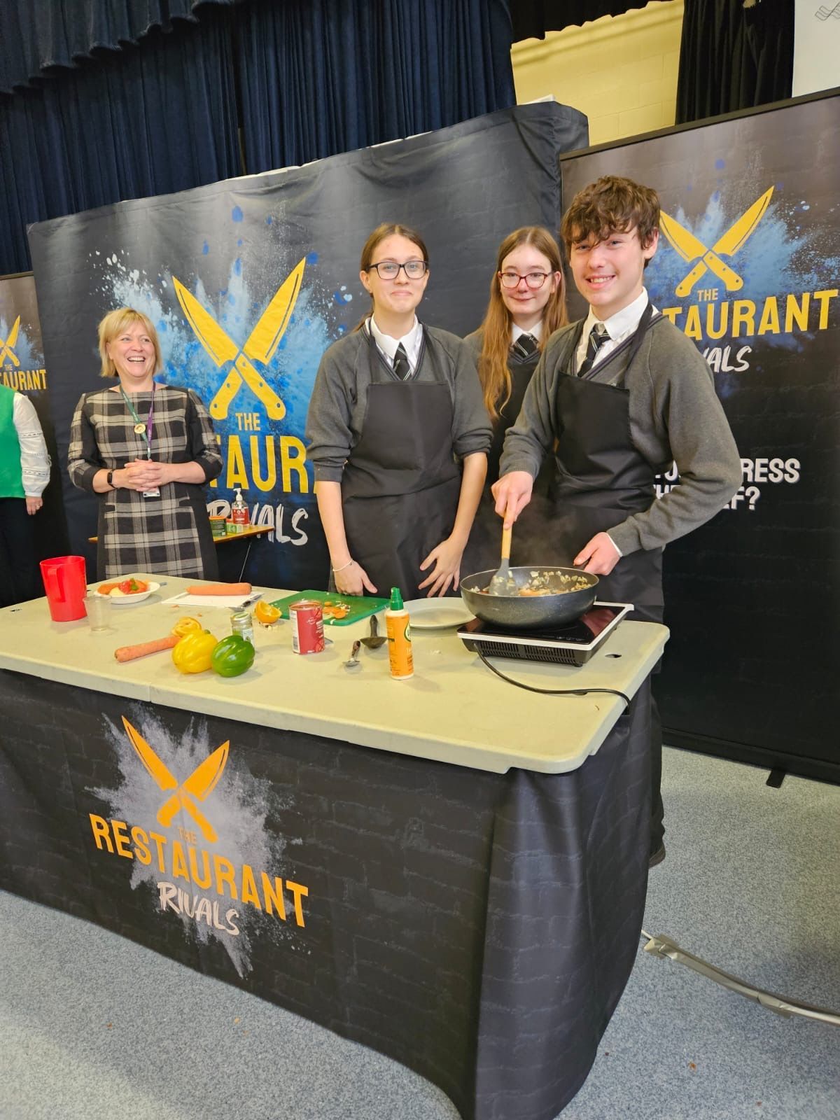 Three students cook on a table with a 