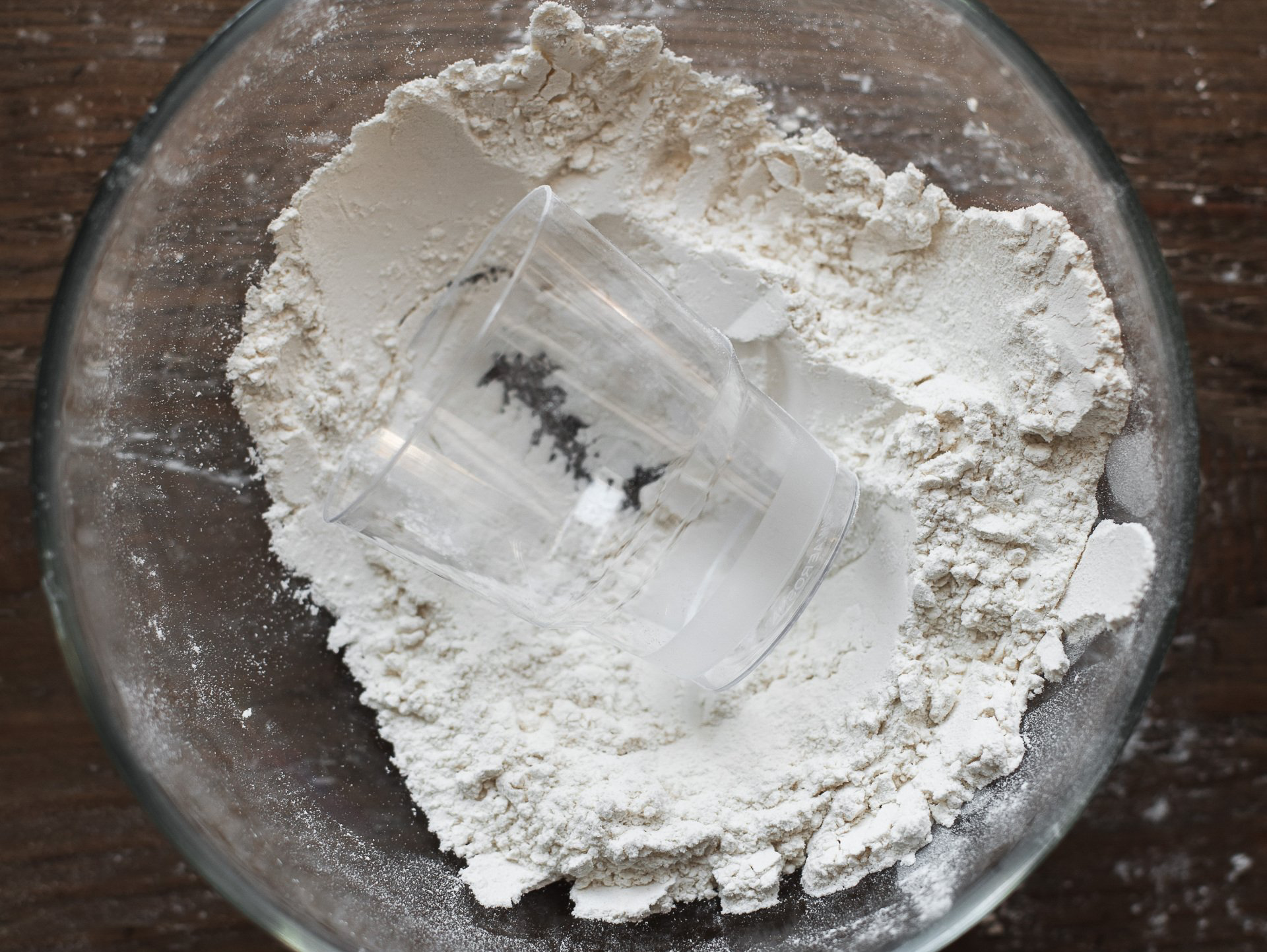 Clear glass dish with a pile of flour, holding a clear plastic sheet with black patterns.
