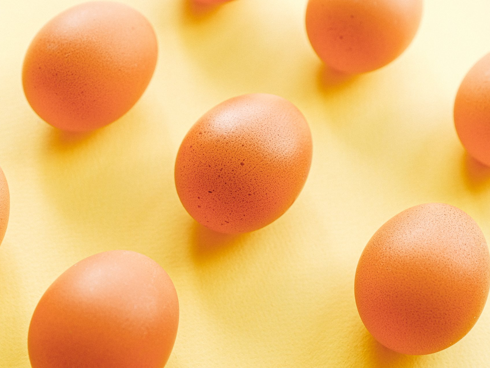 Brown eggs scattered on a yellow surface.