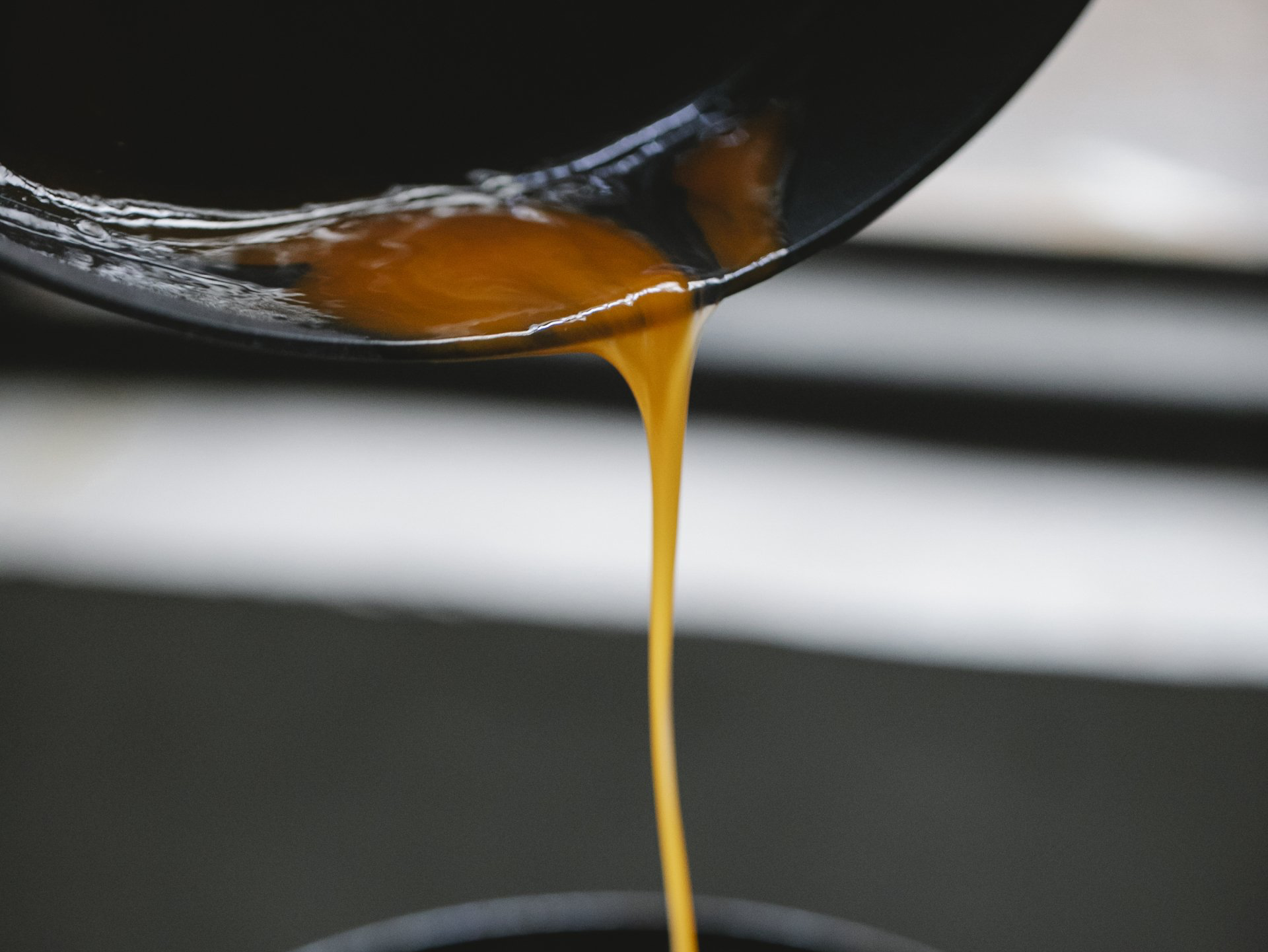 Brown liquid, likely caramel, pouring from a black pan.