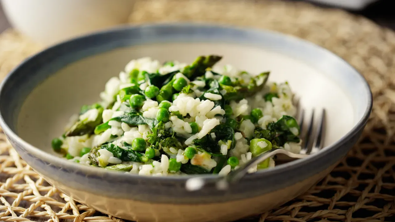Bowl of risotto with green asparagus, peas, and spinach.