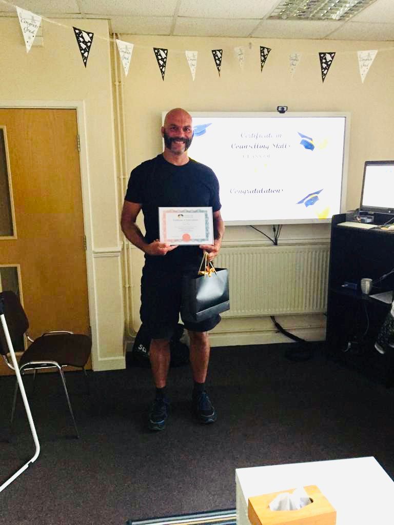 Man holding certificate in room with whiteboard, holding a purse.