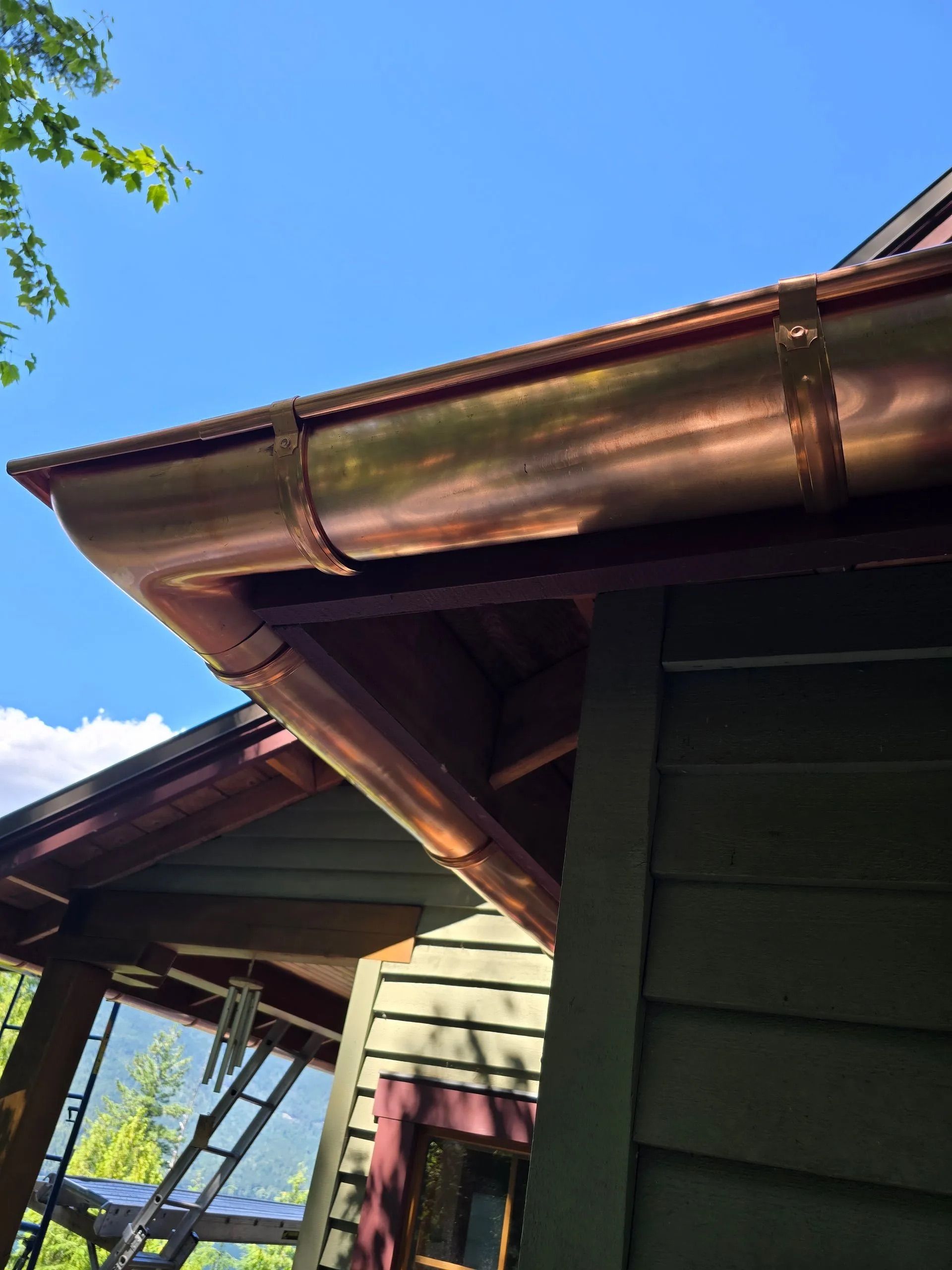 Wooden house roof with exposed beams and a blue sky in the background
