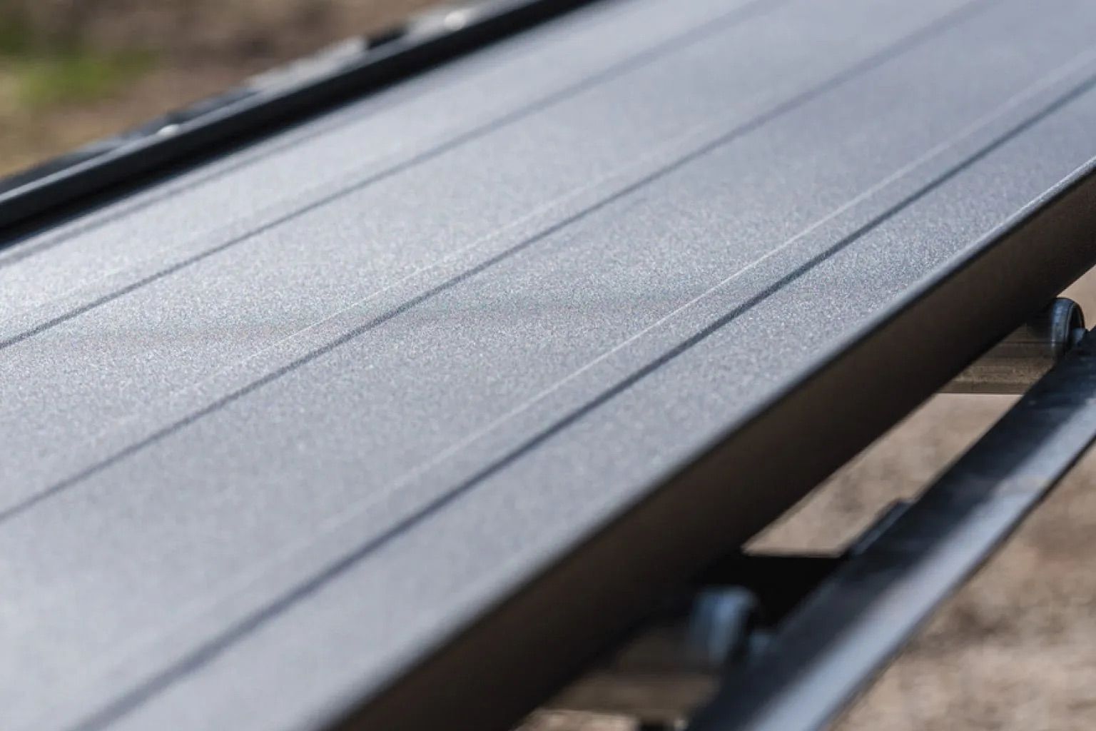 Close-up of a black metal roof rack bar on a vehicle outdoors