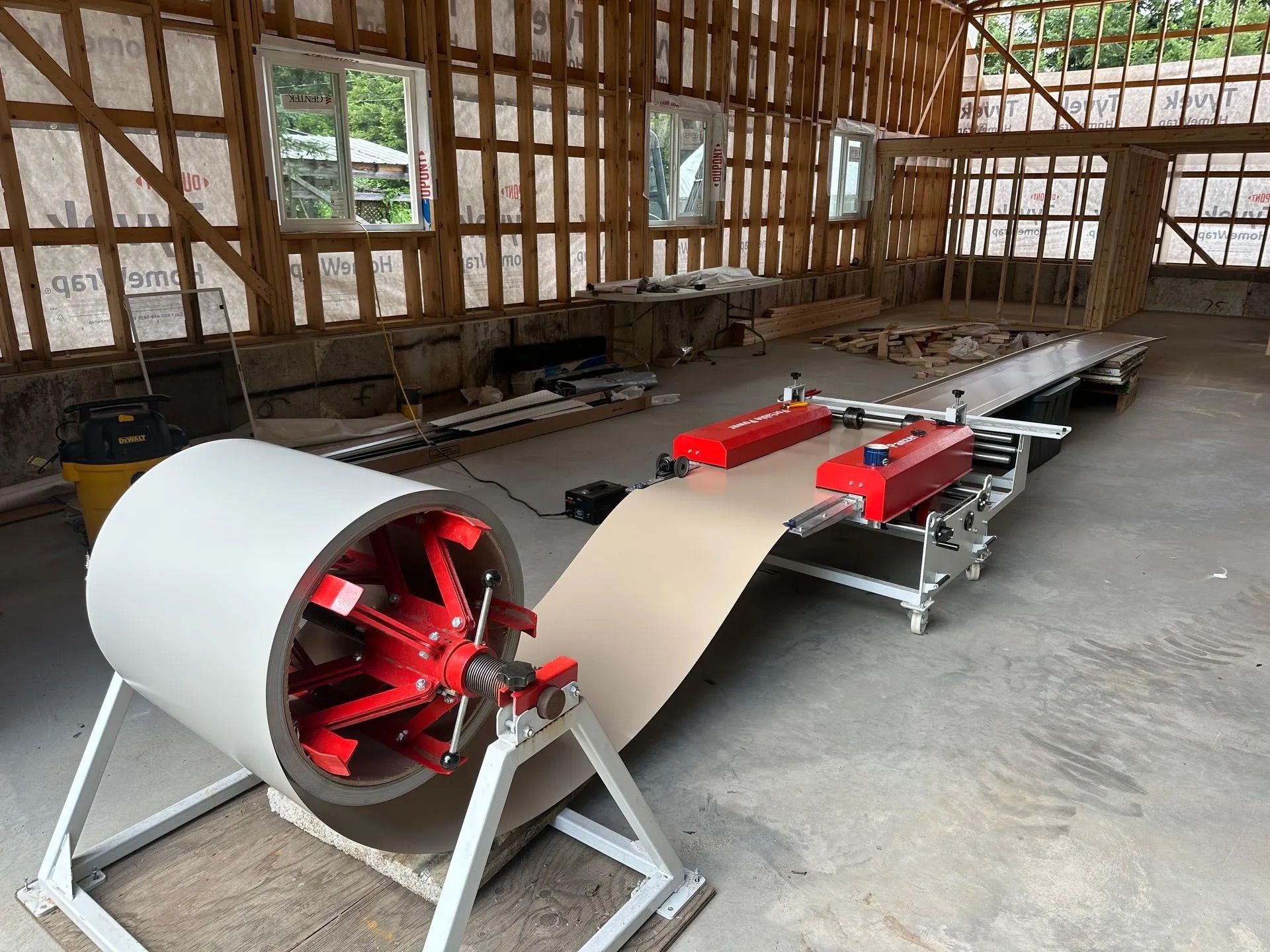 Red-and-silver industrial machine setup with a long belt in a wooden workshop.