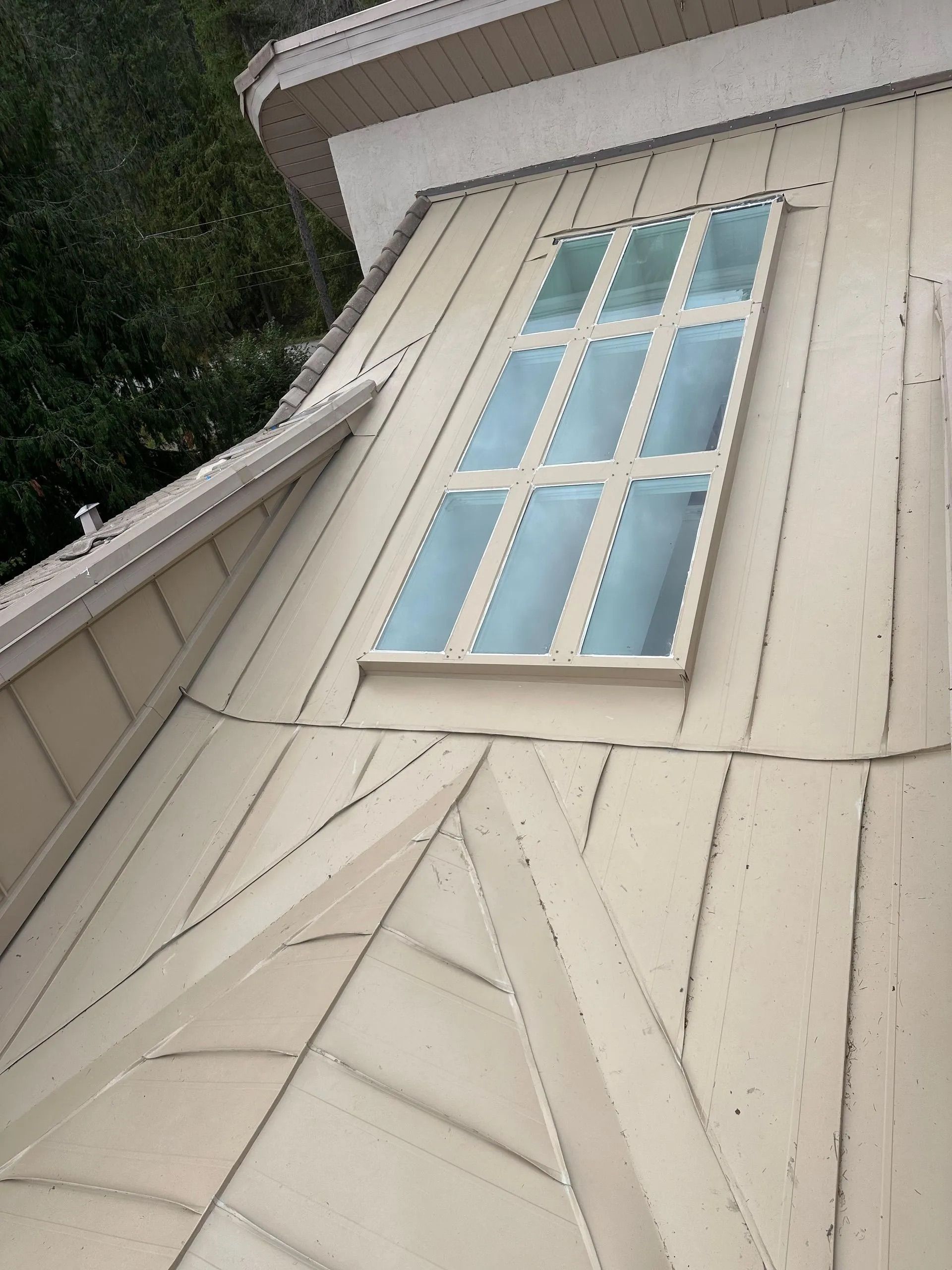 White house exterior with a tall window and beige siding viewed from below