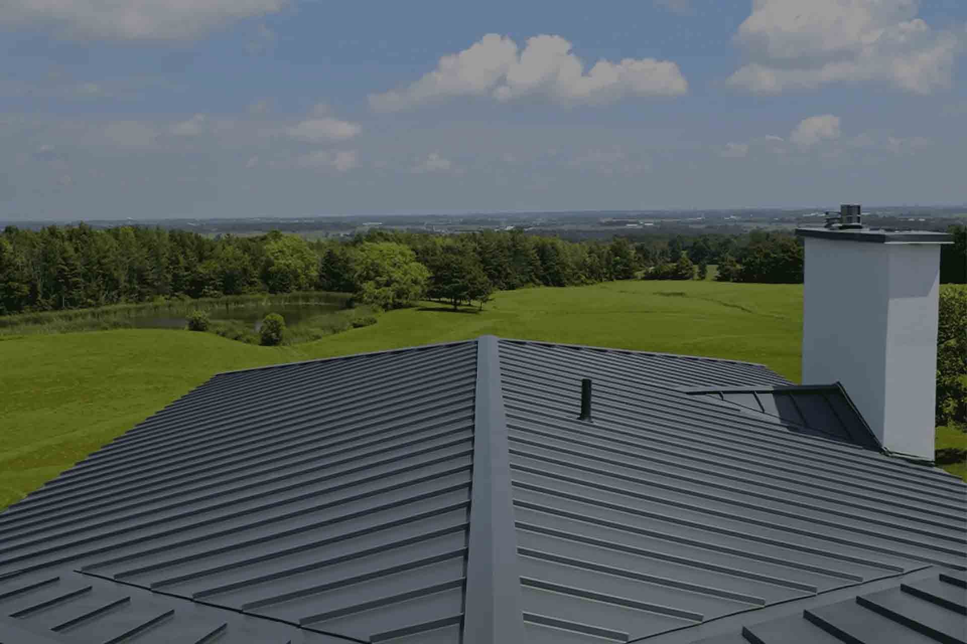 Rooftop view of a green landscape under a blue sky, with a chimney on the right.