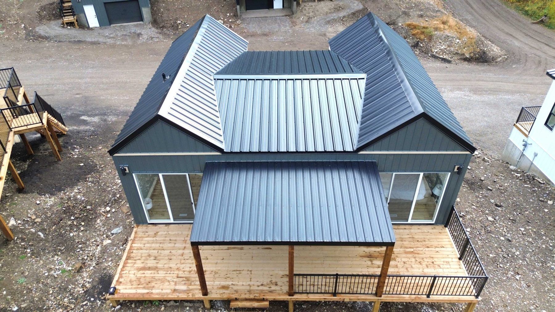 Overhead view of a small dark house with a metal roof and front porch on a wooden deck.