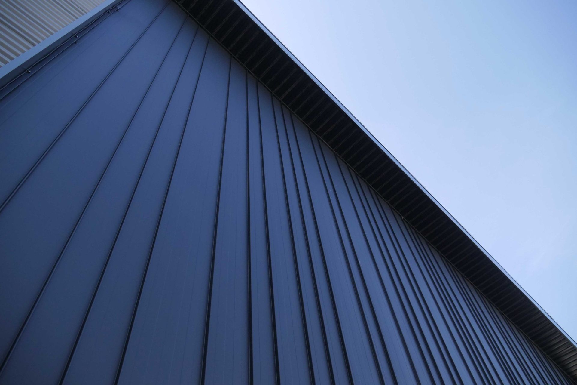 Diagonal view of a blue corrugated metal building against a clear sky
