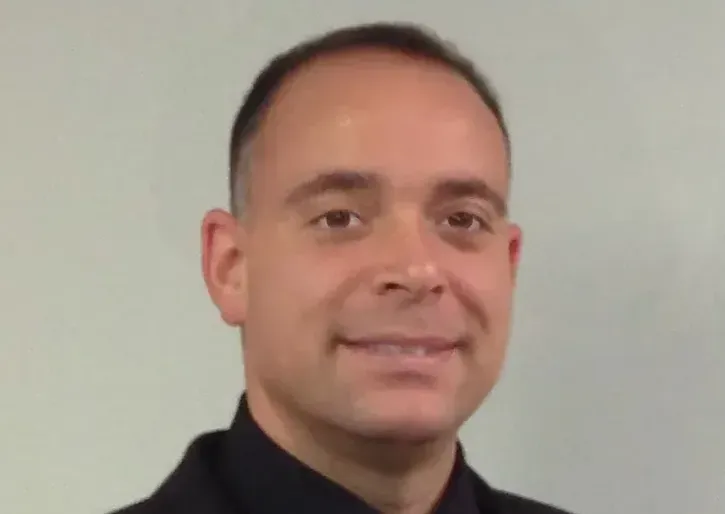 A man in a black shirt is smiling for the camera.