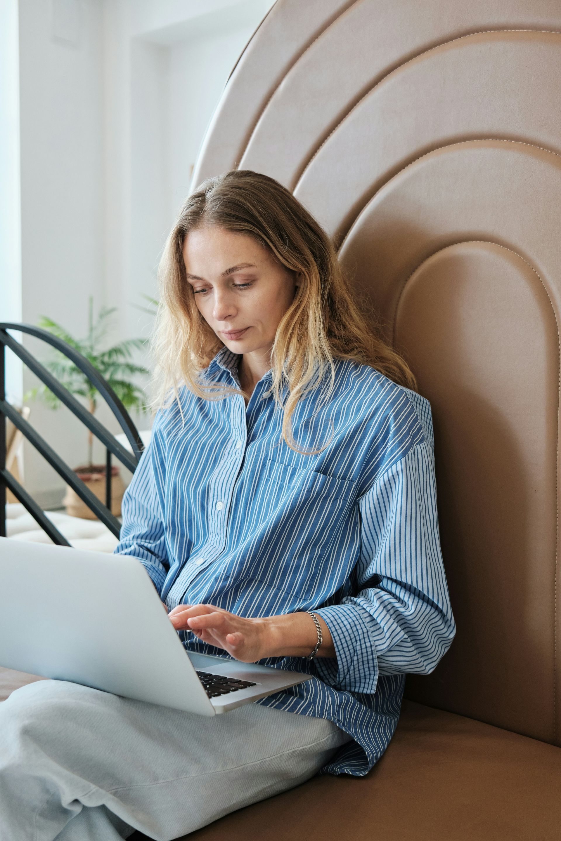 A woman is sitting on a couch using a laptop computer.
