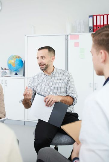 A group of people are sitting in a circle having a meeting.