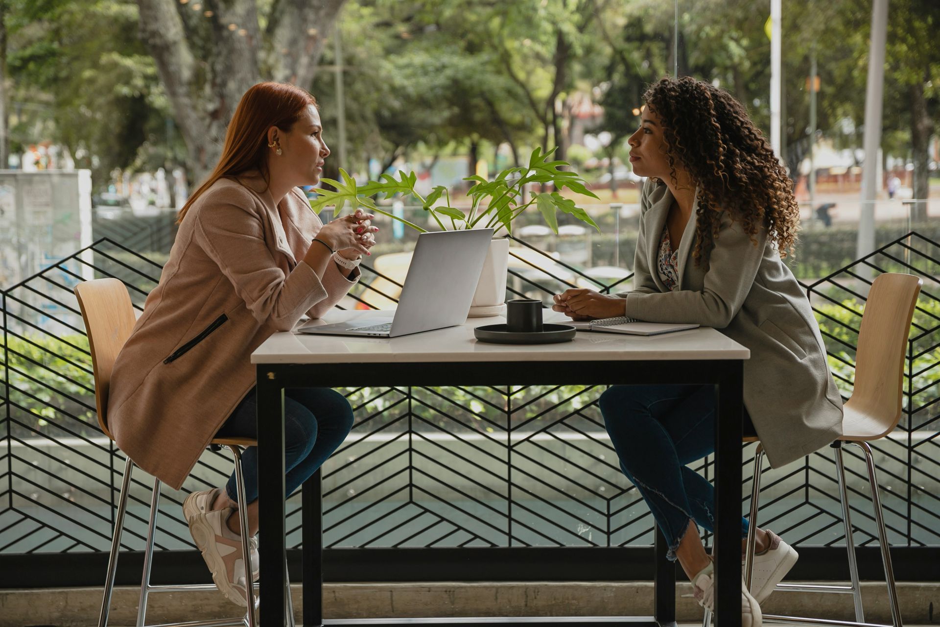 Two women are sitting at a table with a laptop.