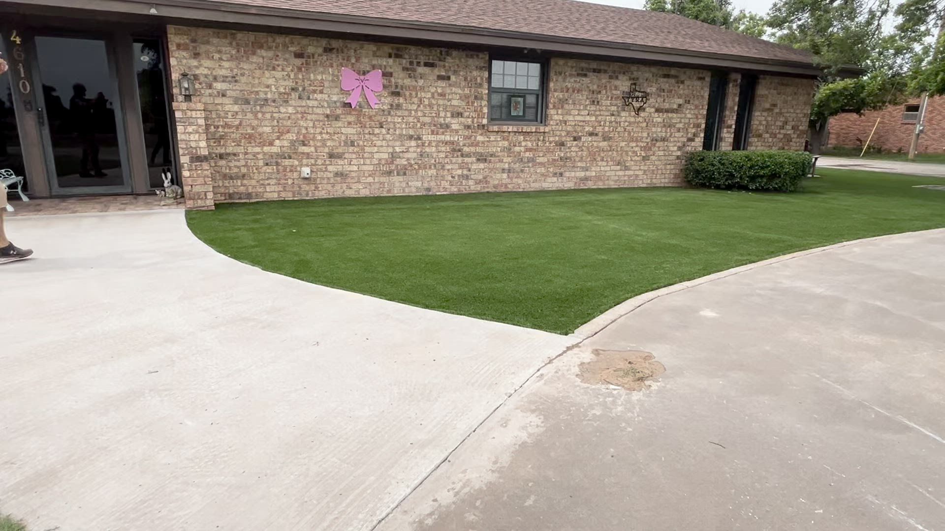 Brick house with a curved concrete driveway and green lawn in front