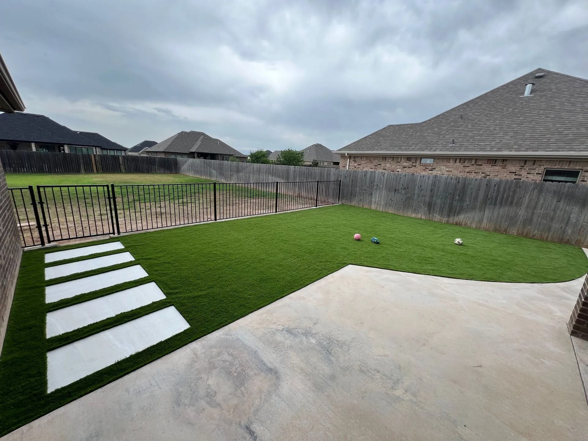 Aerial view of a house with a backyard pool, lawn, and large concrete pad in a rural area