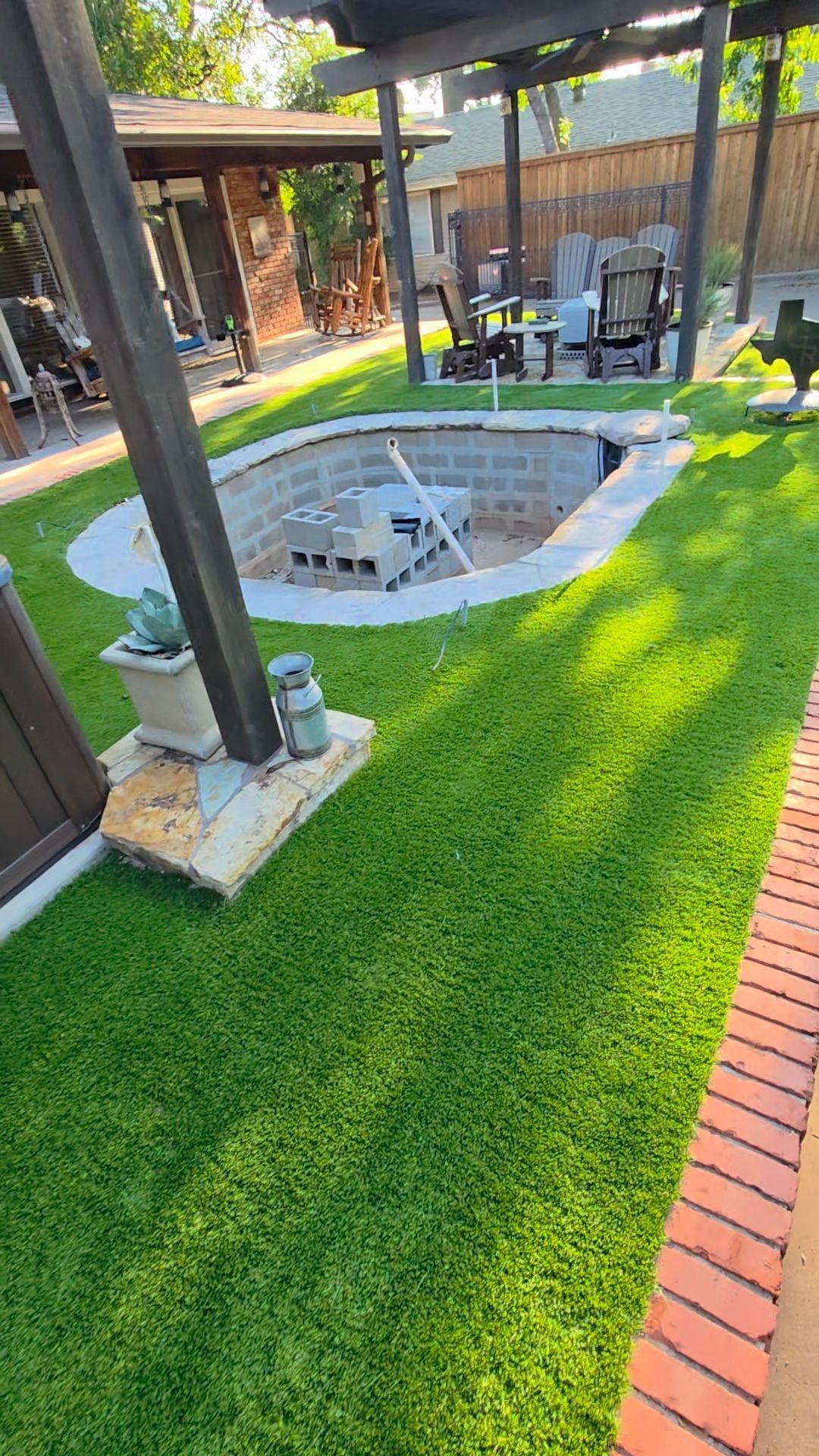Backyard patio with a covered hot tub, green lawn, and outdoor seating area