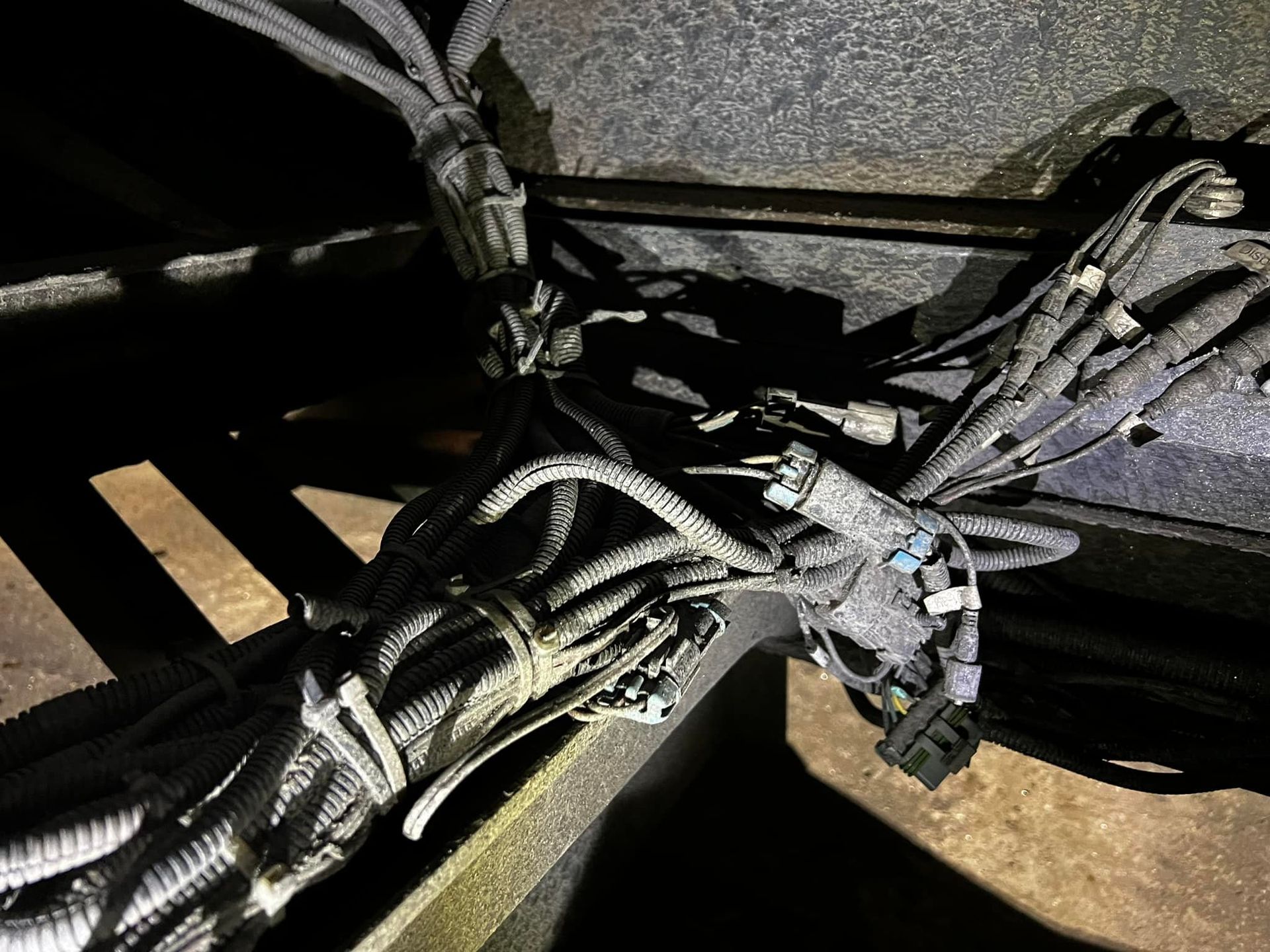 Bundled electrical wiring, dark gray against a dark surface.