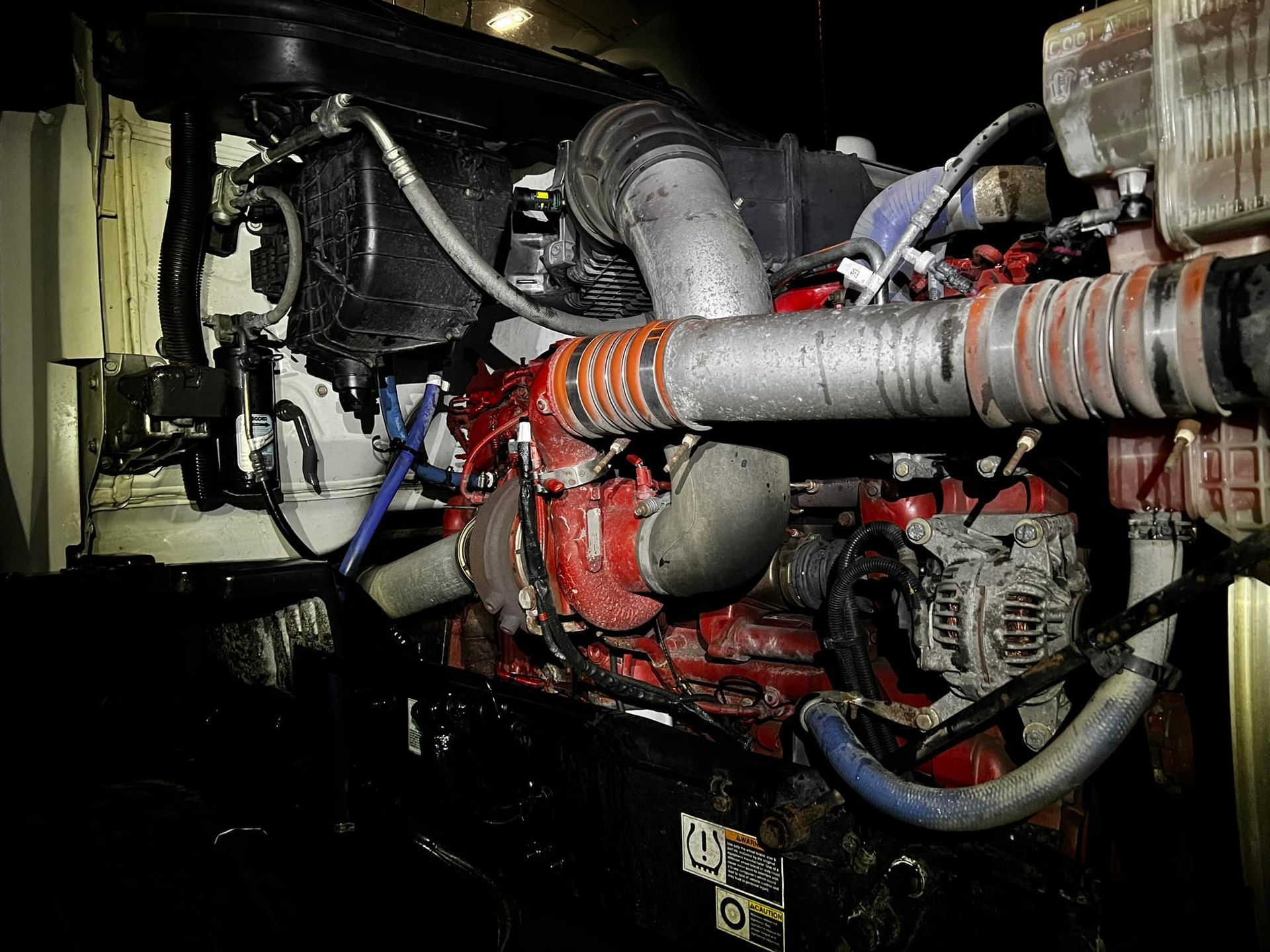 A truck engine, mostly red and silver, with various tubes and wires.