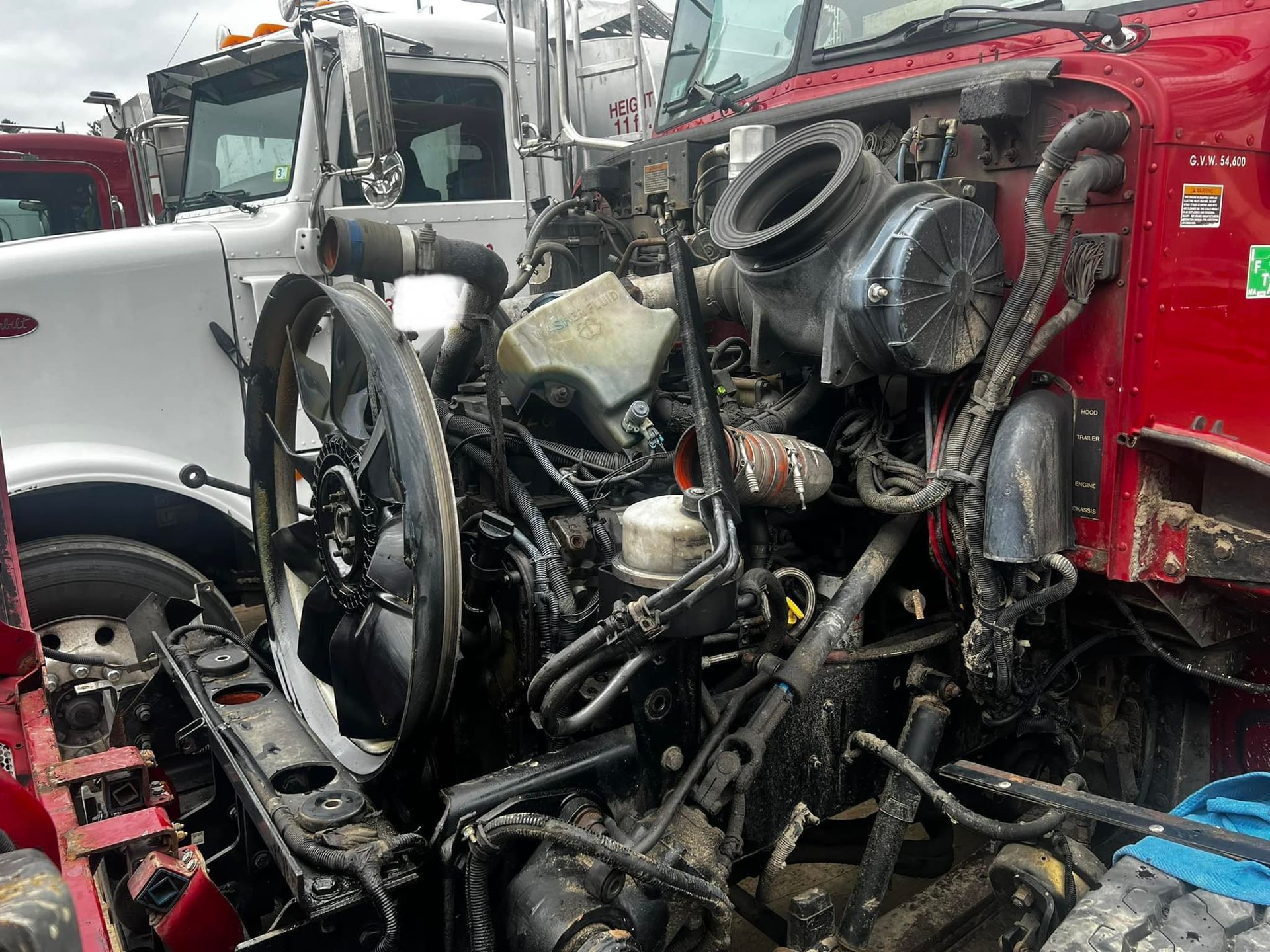 Red and white semi-truck engines in a junkyard. Exposed engine components and damage are visible.