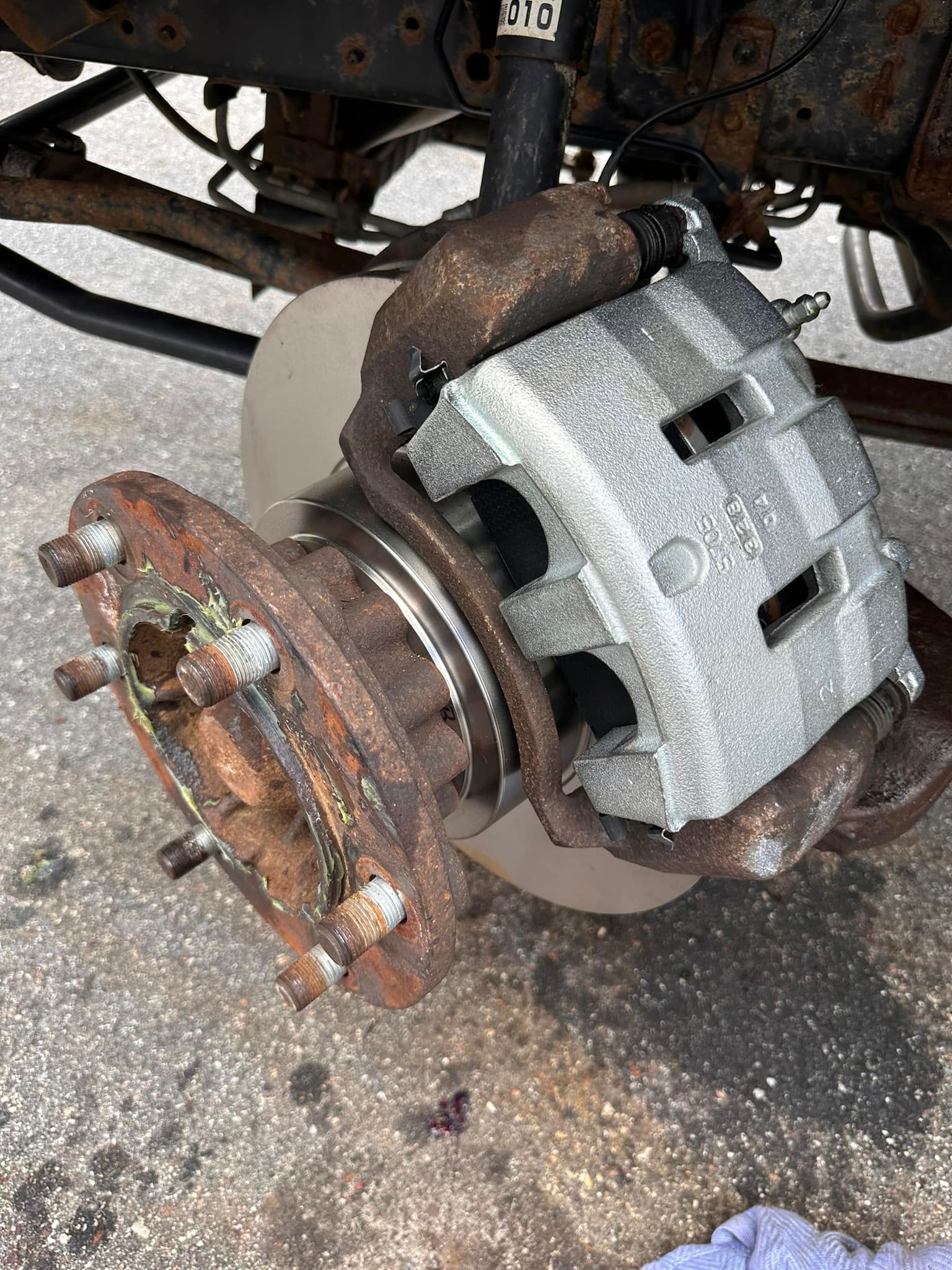 Rusty car brake assembly with rotor, caliper, and hub.