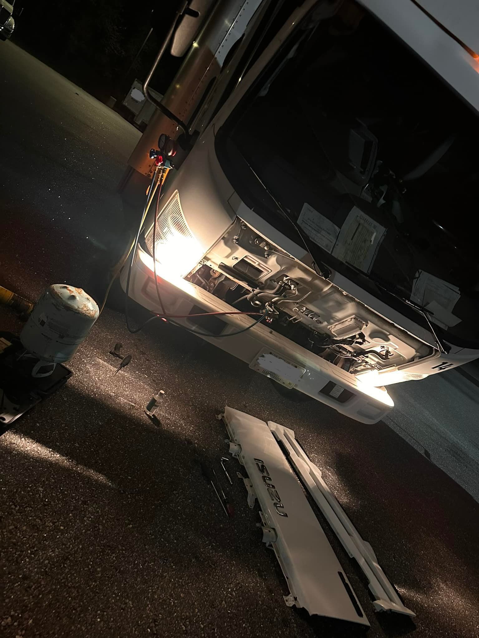 White vehicle, possibly a bus, damaged on a dark road with debris.