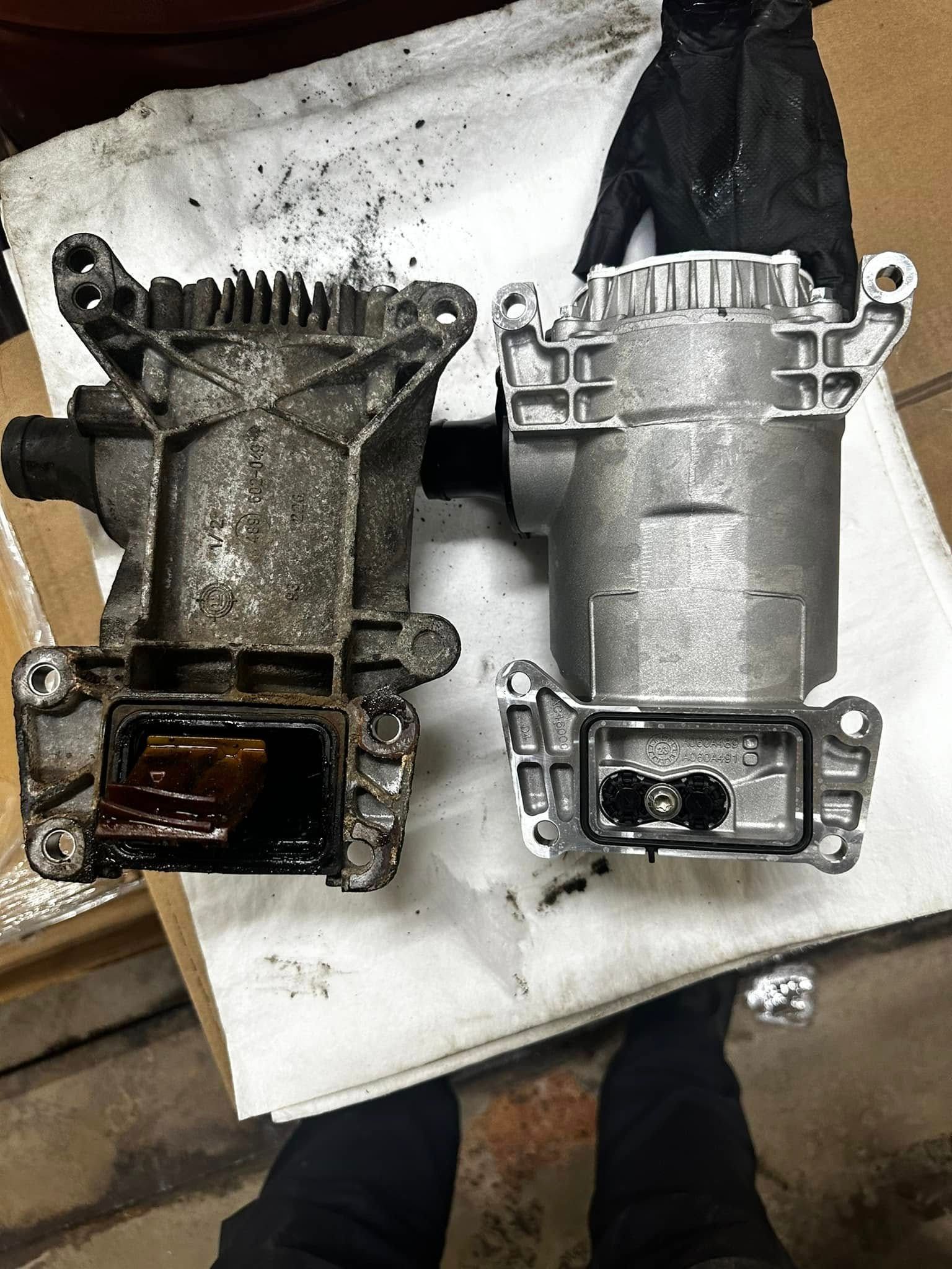 Two car parts, one dirty and one clean, are on a white surface. A person wears a black glove.