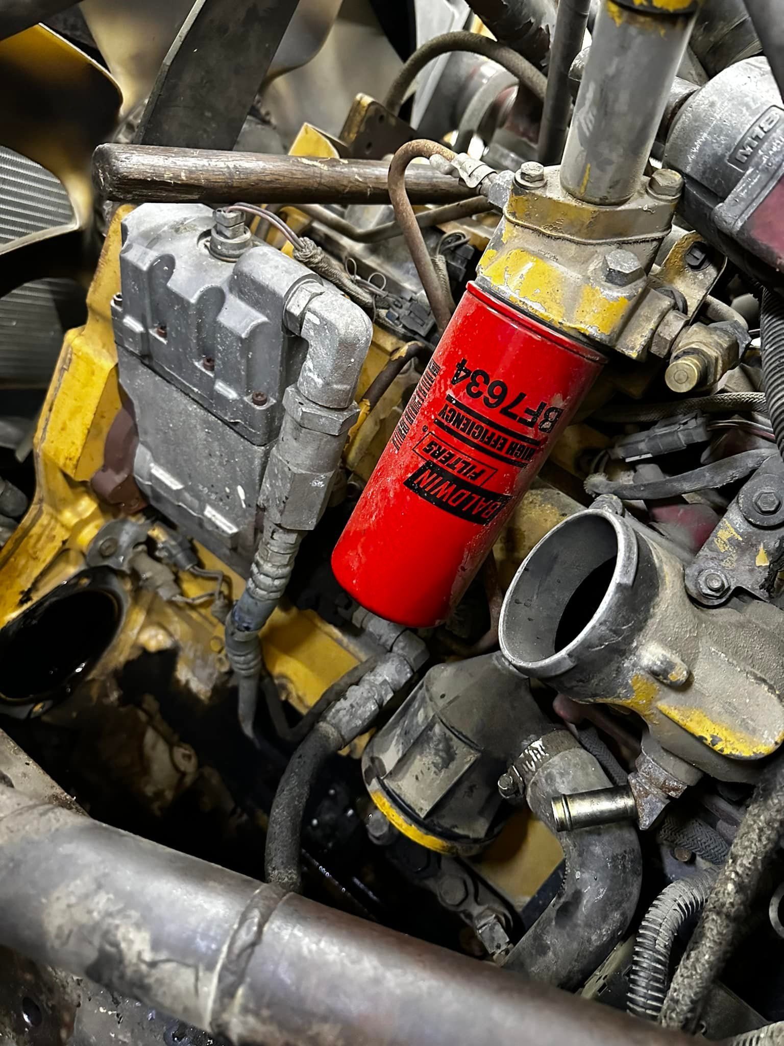 Diesel engine with a red fuel filter, various hoses, and electronic components.