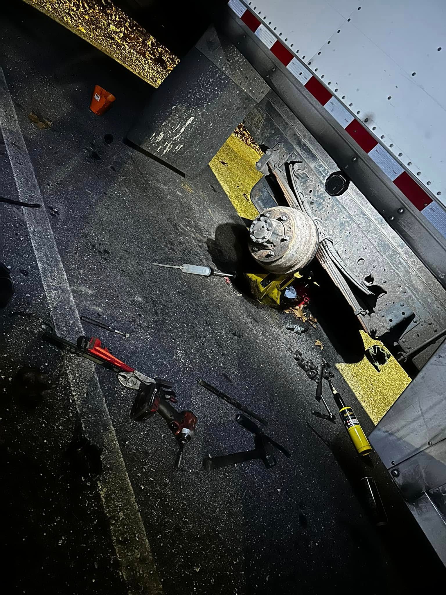 Overhead view of a vehicle accident scene at night. A crushed vehicle, tools, and debris are visible on a road.
