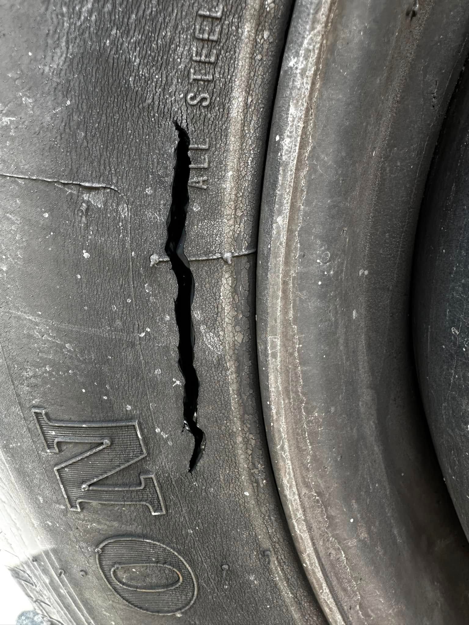 Close-up of a damaged tire with a large crack along the sidewall, possibly causing structural failure.