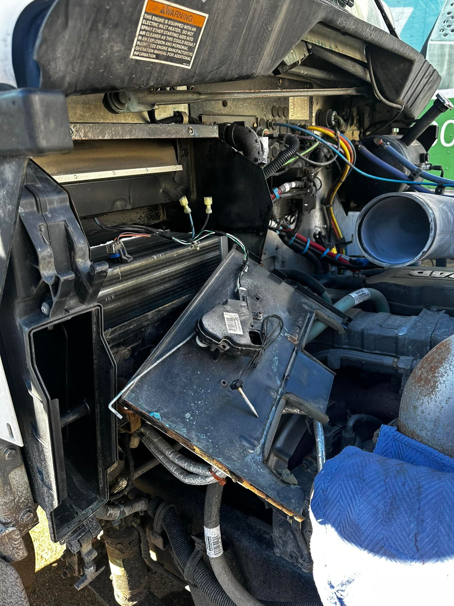 Damaged truck engine compartment; black metal, wires, and broken components.