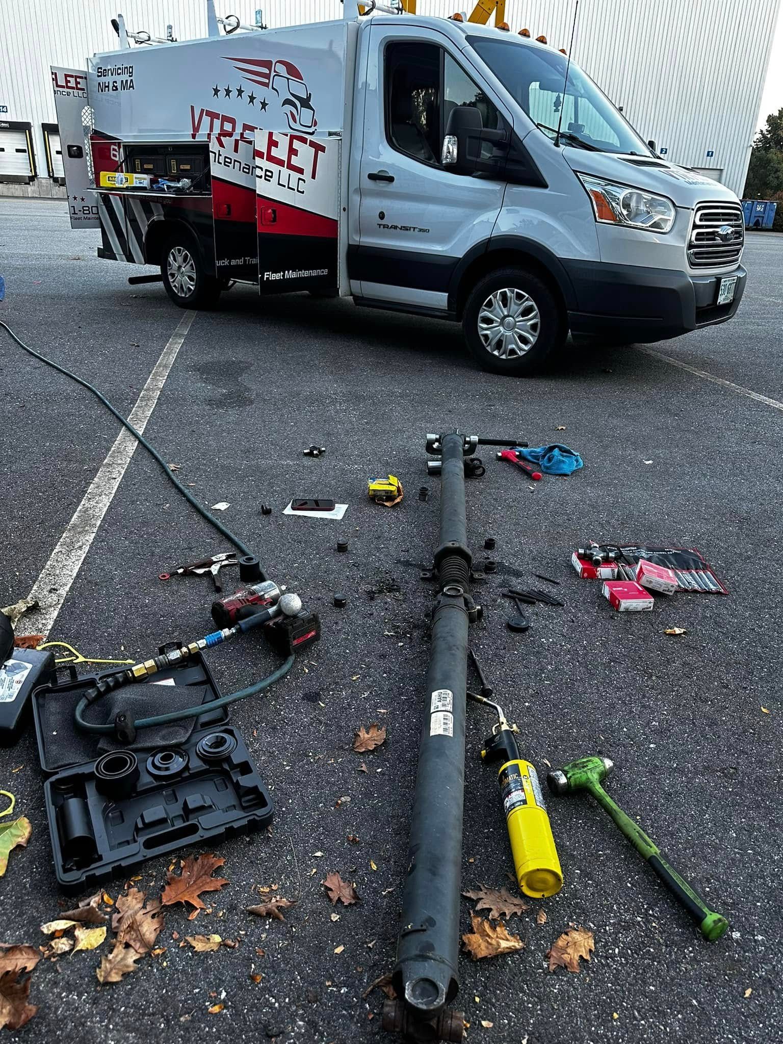 A work van parked in a parking lot with tools and parts scattered on the ground.
