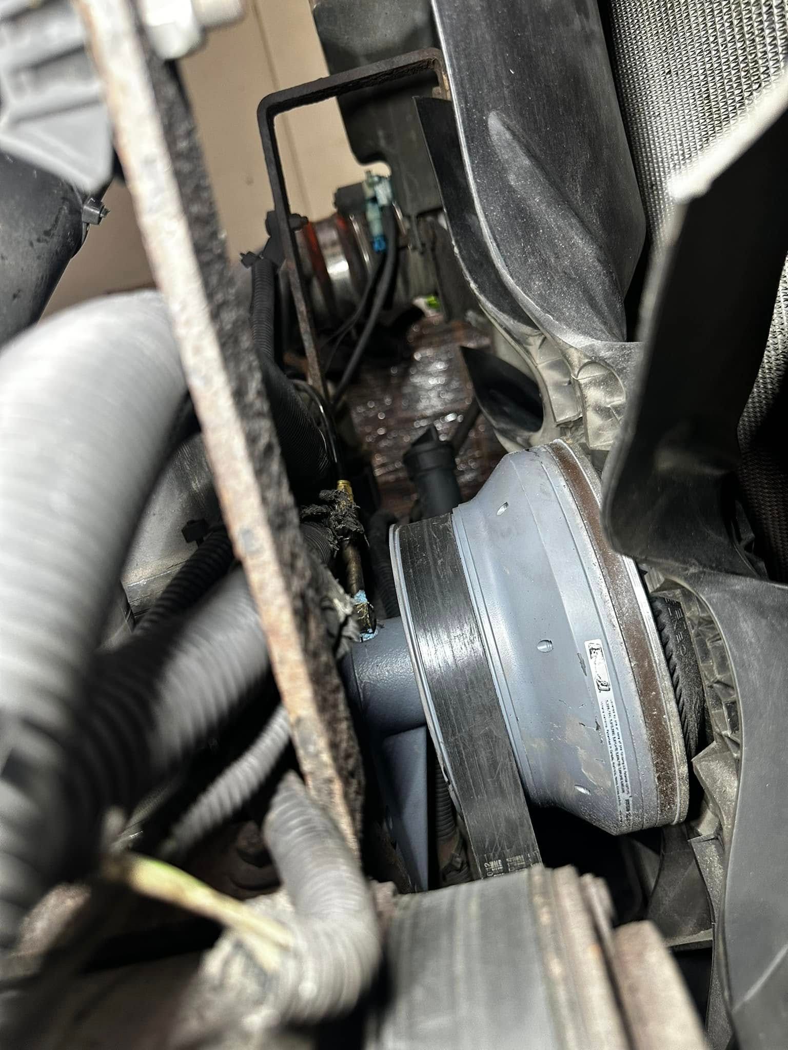 Engine compartment with a fan belt, radiator hose, and other engine components.