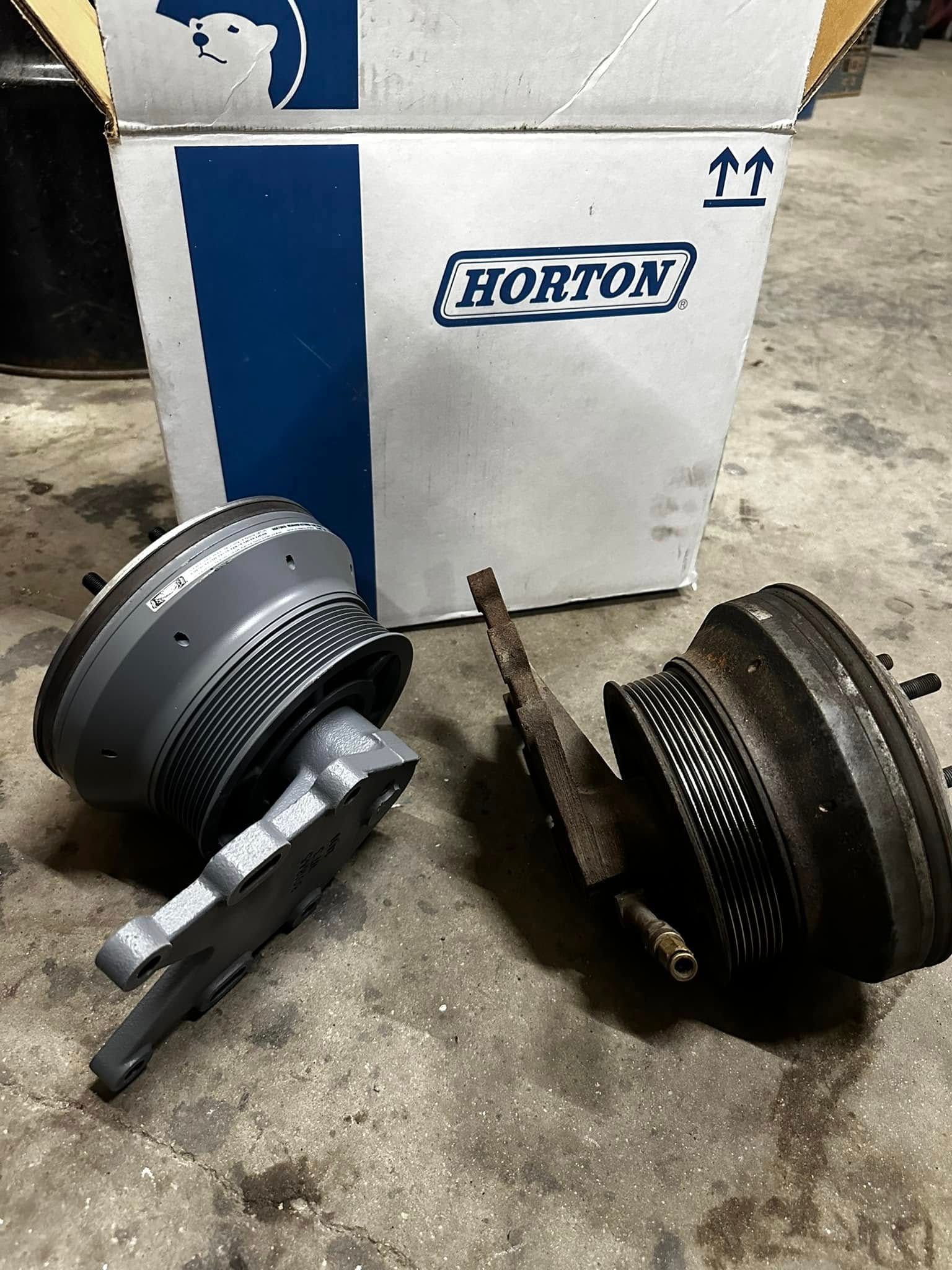 Two automotive fan clutches and a box on a concrete floor. The box is labeled 