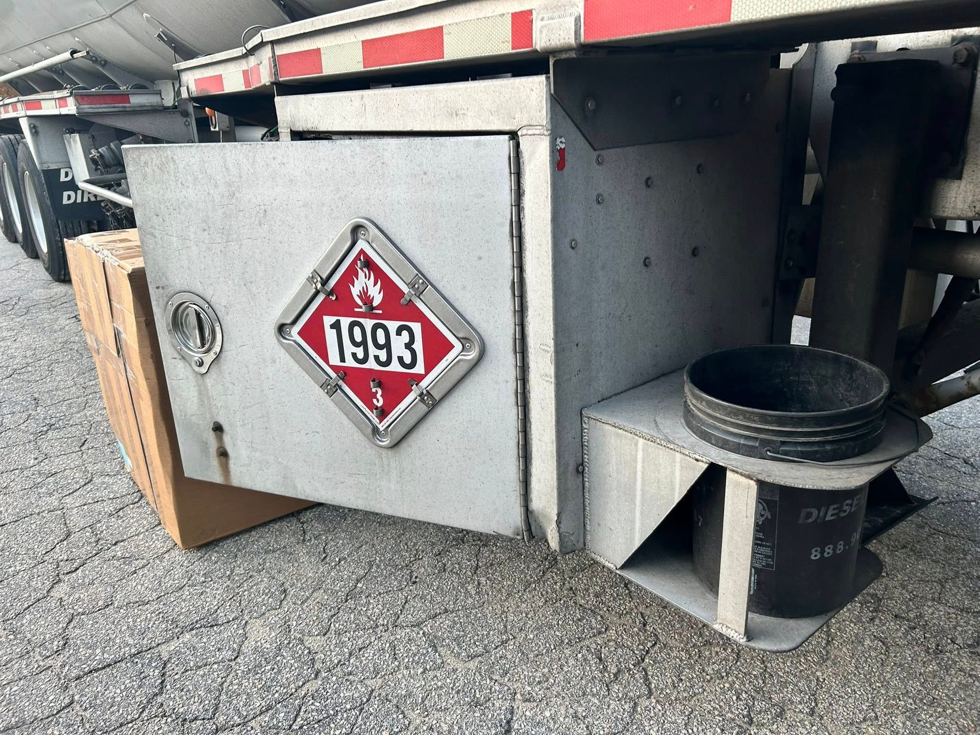 A close-up of a fuel tanker's storage compartment, with a 1993 flammable liquid placard visible.