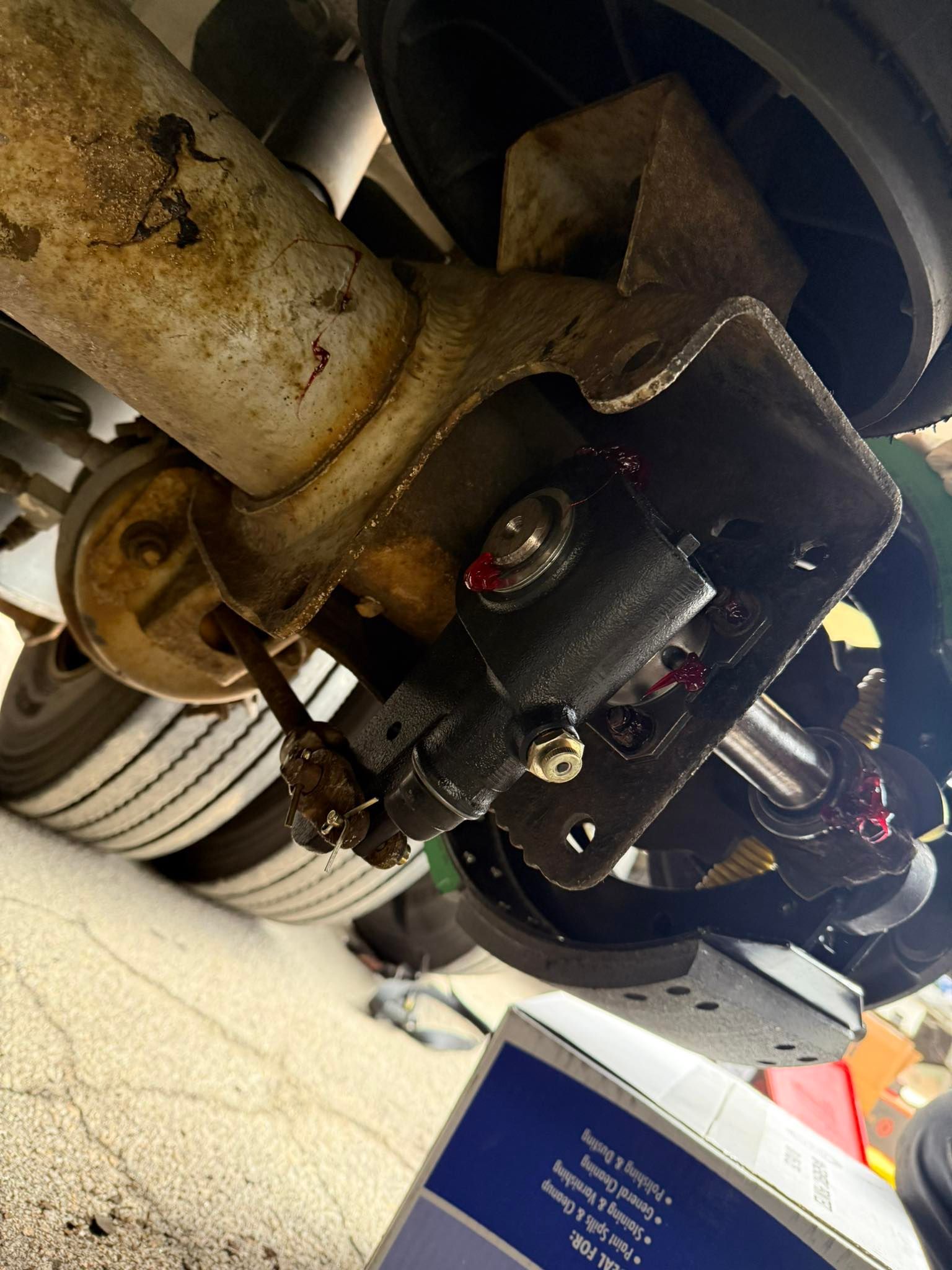 Truck undercarriage with brake components; rusted parts, various nuts, and bolts visible.