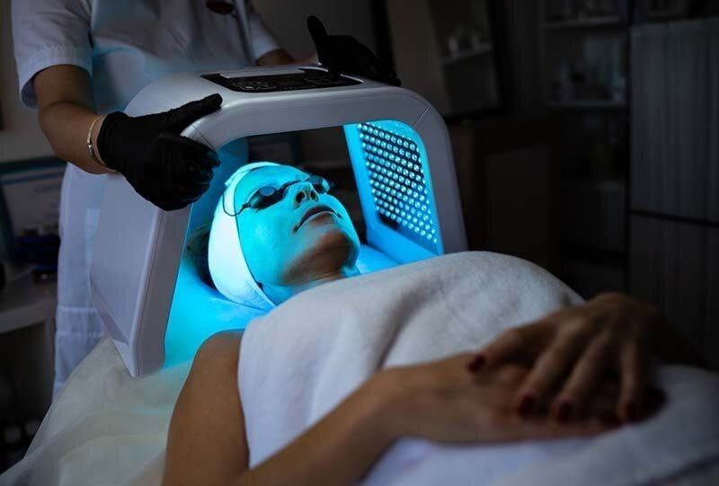 Woman undergoing blue light therapy treatment at a spa.