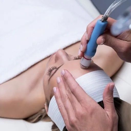 Person receiving facial treatment with a handheld device on forehead, in a clinic.