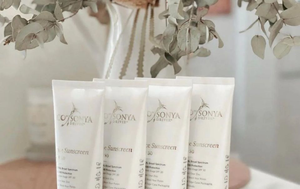 Four white tubes of Sonya Skin Care products with floral background.