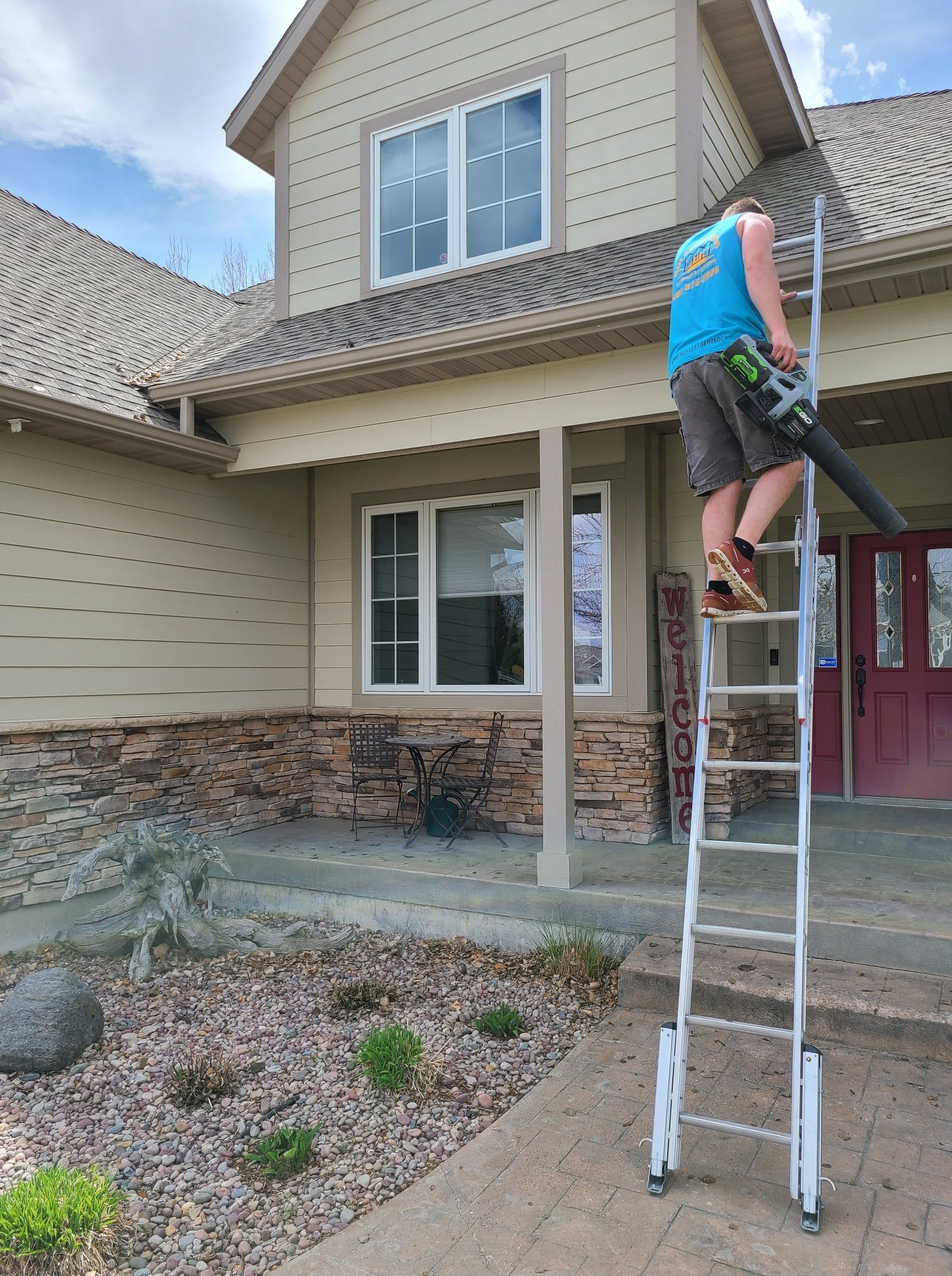A man on a ladder cleaning the roof of a house