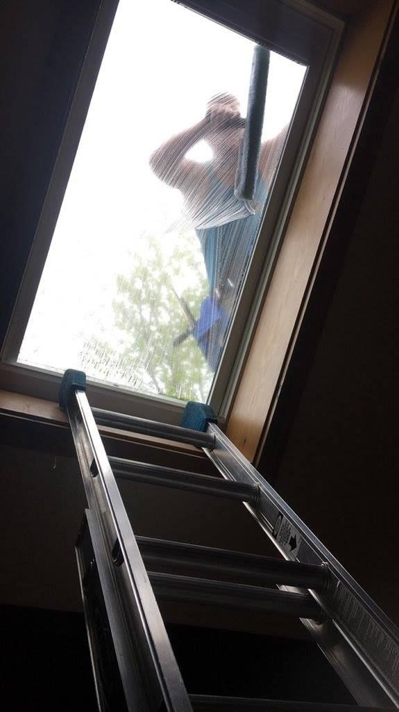 A man is cleaning a window with a ladder.