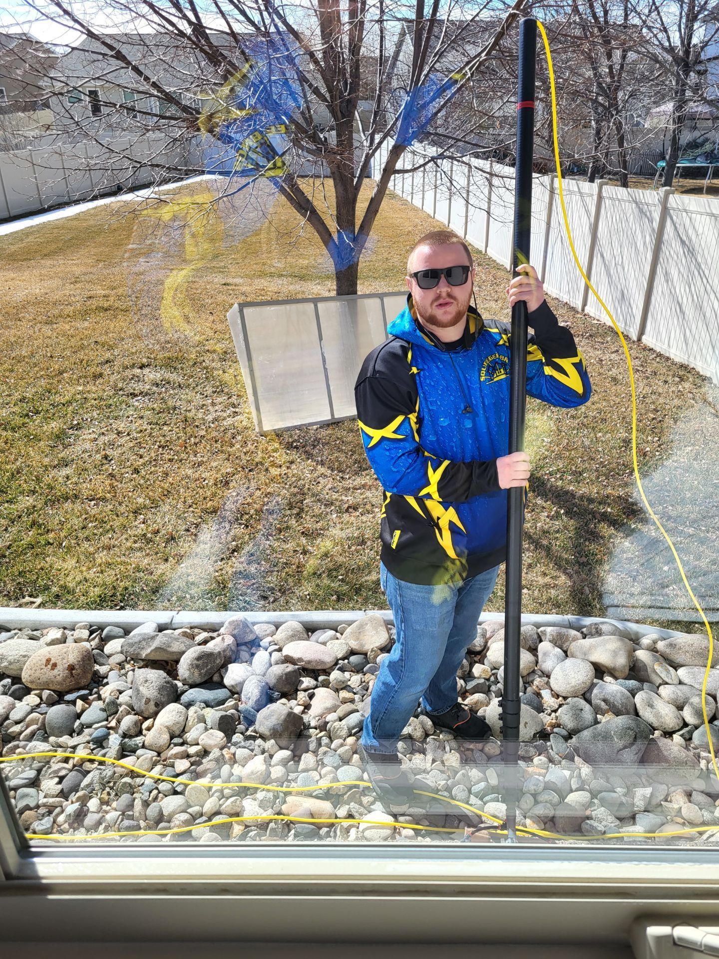 A man in a blue jacket is holding a pole in front of a window