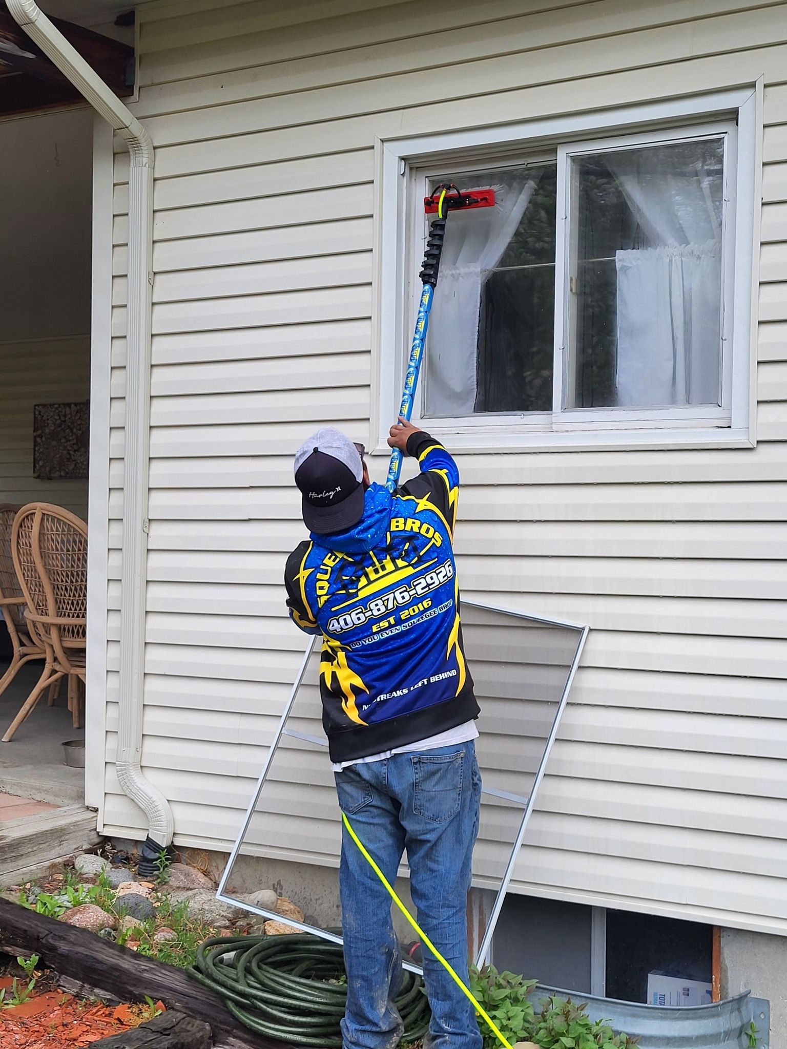 A man in a blue and yellow shirt is cleaning a window