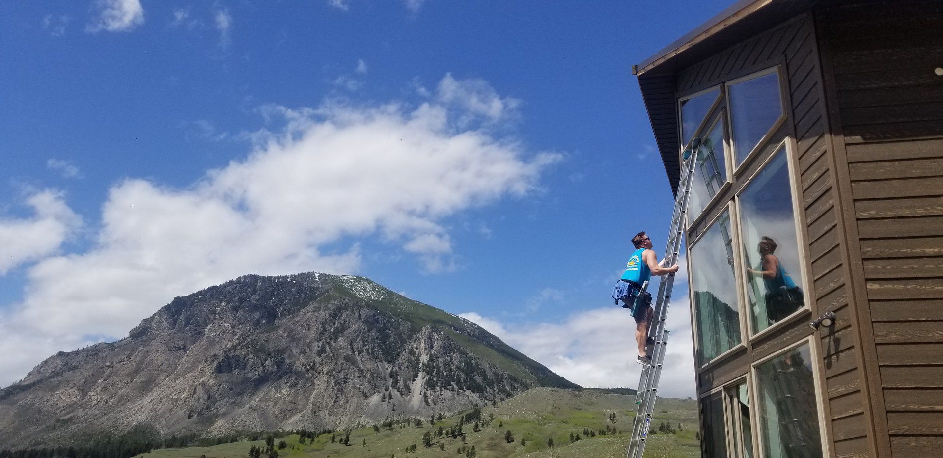 A man on a ladder is cleaning the windows of a building.